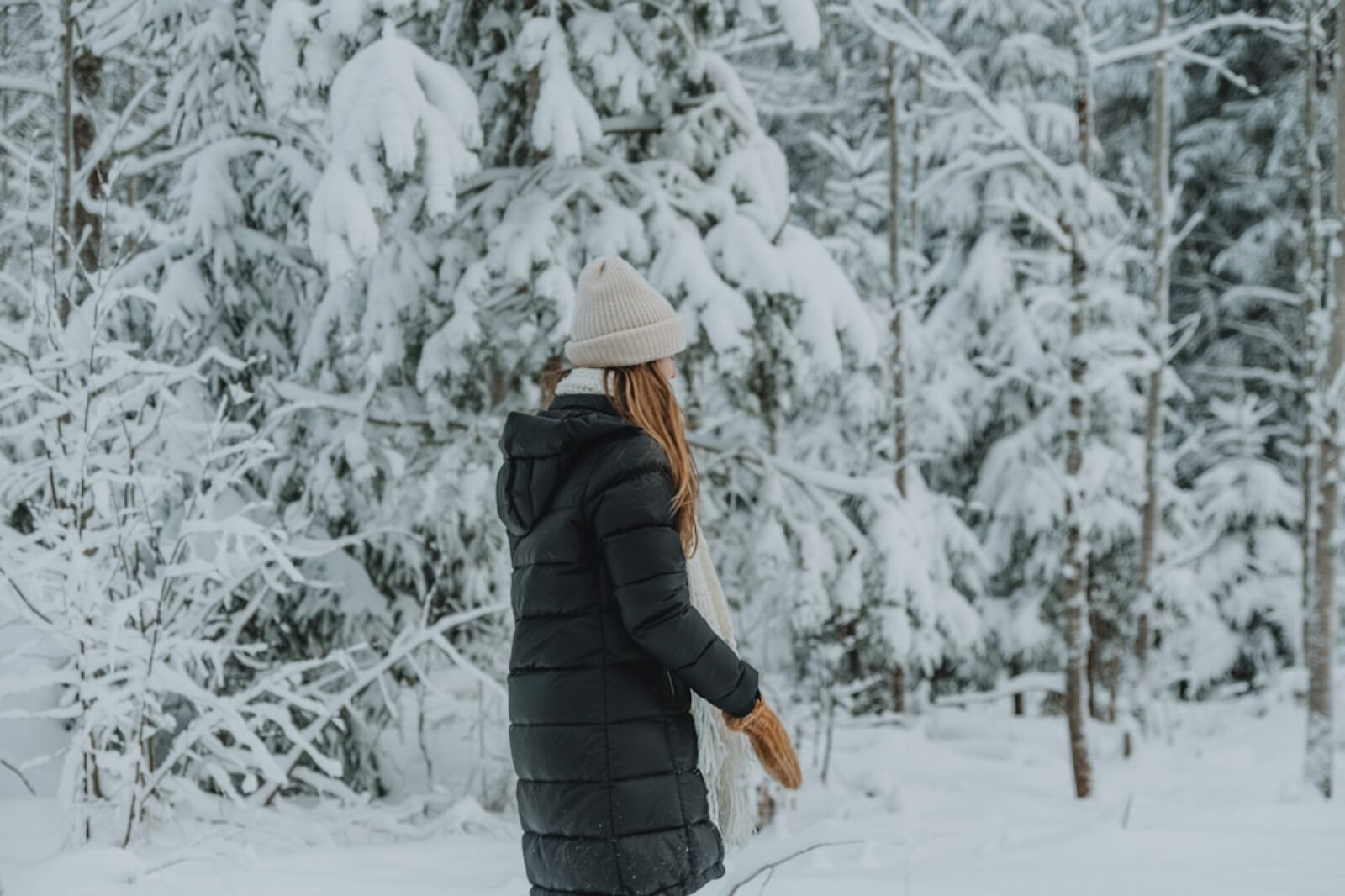 a woman walking through a snow covered forest