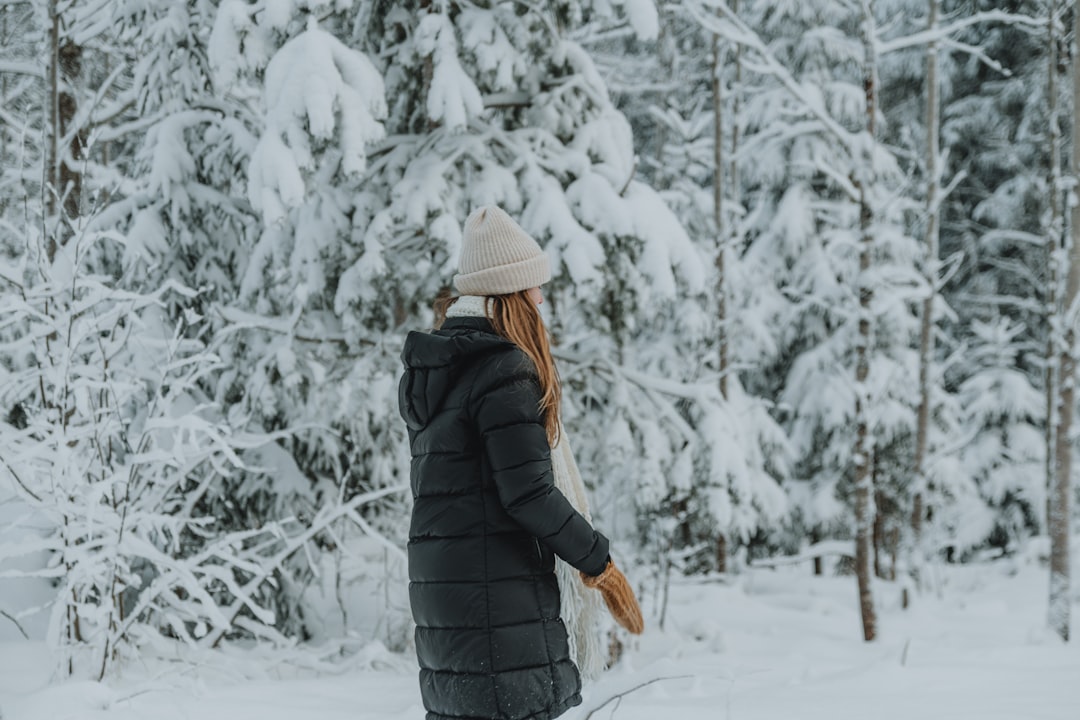 a woman walking through a snow covered forest